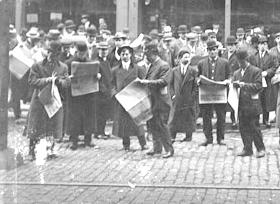 Men and boys standing and reading newspapers outside the Chicago Daily News building at 123 North Wells Street, 1911